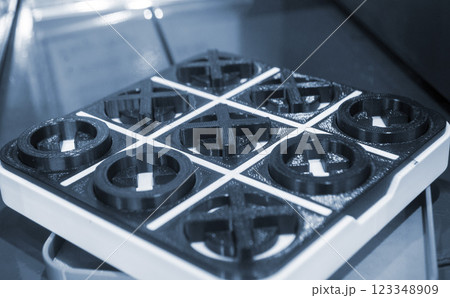 Model of the toy Tic-tac-toe printed on 3D printer close-up. Object created on 3D printer from molten plastic of black and white color. 3D printing technology. Additive modern progressive technologies 123348909