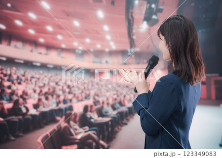 大勢の聴衆が集まるホールで司会をする若い女性 123349083