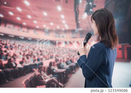 大勢の聴衆が集まるホールで司会をする若い女性 123349086