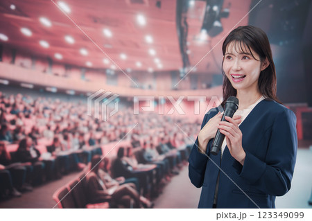 大勢の聴衆が集まるホールで司会をする若い女性 123349099