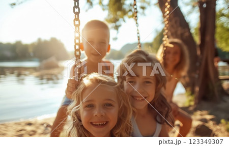 happy kids swinging at sunny summer park, cheerful and joyful boys and girls swing and play, children have fun at holidays 123349307