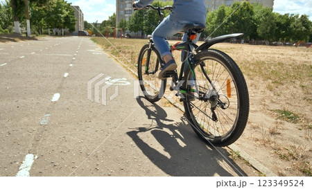 A twelve-year-old girl riding her bike on a warm summer day. Bicycle wheel close up. A twelve-year-old girl riding her bike on a warm summer day. Bicycle wheel close up. 123349524