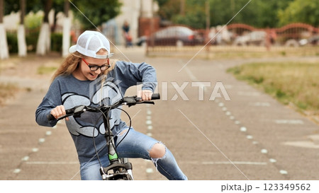Child blond girl riding a bicycle on a bike path in summer Child blond girl riding a bicycle on a bike path in summer 123349562