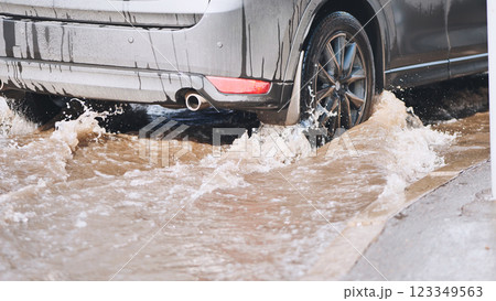 Muddy vehicle splashing through roadside puddle during wet, overcast weather conditions Muddy vehicle splashing through roadside puddle during wet, overcast weather conditions 123349563