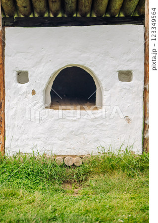 Whitewashed outdoor stove with wooden roofing in a grassy area, showcasing traditional russian construction Whitewashed outdoor stove with wooden roofing in a grassy area, showcasing traditional russian construction 123349564