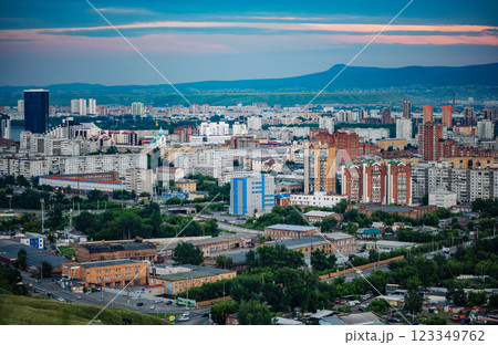 Krasnoyarsk cityscape revealing urban landscape, residential zones, winding streets, verdant greenery, mountain silhouettes against dramatic sunset lighting Krasnoyarsk cityscape revealing urban landscape, residential zones, winding streets, verdant greenery, mountain silhouettes against dramatic sunset lighting 123349762