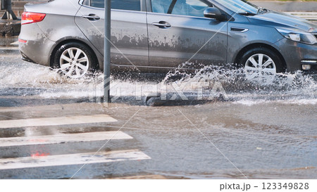 Gray car splashing through flooded street after heavy rain, creating large spray of water Gray car splashing through flooded street after heavy rain, creating large spray of water 123349828