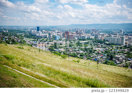 Panoramic view of krasnoyarsk, russia, showcasing the cityscape with green hills in the foreground and a cloudy blue sky. 123349829