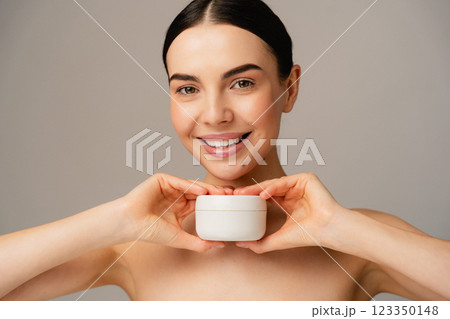 Smiling Woman Holding Skin Care Cream Jar in a Studio Setting Smiling Woman Holding Skin Care Cream Jar in a Studio Setting 123350148
