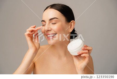 Smiling Woman Applying Moisturizing Cream With a Cheerful Expression 123350190