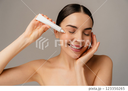 Smiling Person Applying Eye Cream as Part of Daily Skincare Routine 123350265