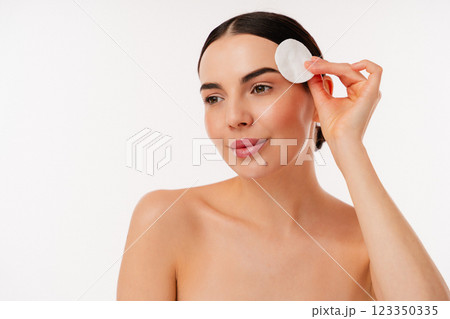 Woman Cleansing Face With Cotton Pad in Minimalist Beauty Routine Woman Cleansing Face With Cotton Pad in Minimalist Beauty Routine 123350335