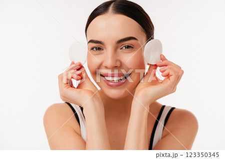 Smiling Woman Performing Skincare Routine with Cotton Pads for Clean and Healthy Skin Smiling Woman Performing Skincare Routine with Cotton Pads for Clean and Healthy Skin 123350345