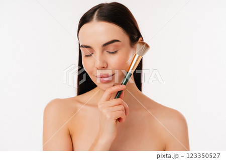 Woman Relaxing With Makeup Brush Demonstrating Natural Beauty and Skincare 123350527