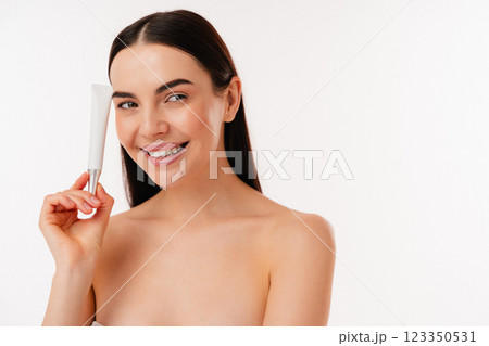 Smiling Woman Holding Skincare Product in a Minimalist Background 123350531