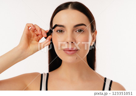 Young Woman Applying Brow Mascara for a Stylish Makeup Look 123351051
