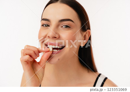 Smiling Person Taking a Health Supplement in a Bright Setting 123351069