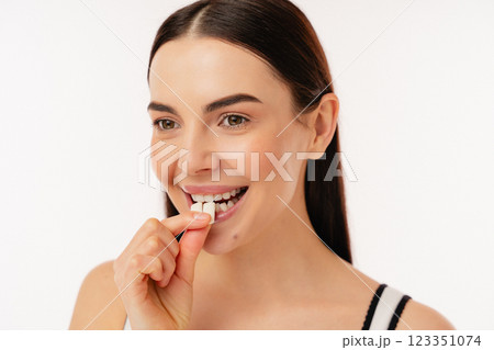 Smiling Individual Enjoying a Piece of Wellness Supplement Smiling Individual Enjoying a Piece of Wellness Supplement 123351074