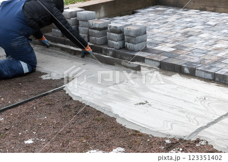 Professional Paver Installing Concrete Bricks for an Outdoor Pathway 123351402