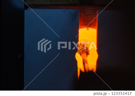 An open furnace with molten glass on a blowpipe inside. Glass blowing An open furnace with molten glass on a blowpipe inside. Glass blowing 123351417