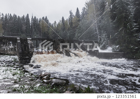 Serene winter landscape featuring a rustic dam streaming water 123351561