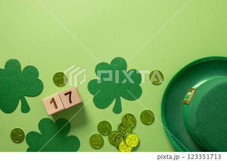 St Patrick's Day frame with Leprechaun hat and traditional decoration, shamrock, clover leaves and green coins on light green background. View from above. St Patrick's Day frame with Leprechaun hat and traditional decoration, shamrock, clover leaves and green coins on light green background. View from above. 123351713