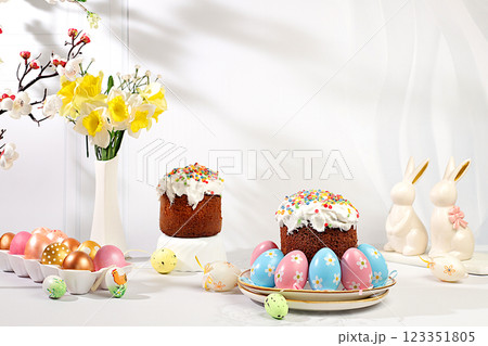 Abstract Easter composition with traditional Russian kulich with meringue and decorated painted eggs on elegant kitchen table with spring sakura flowers and daffodils. Happy Easter concept. Screen Abstract Easter composition with traditional Russian kulich with meringue and decorated painted eggs on elegant kitchen table with spring sakura flowers and daffodils. Happy Easter concept. Screen 123351805