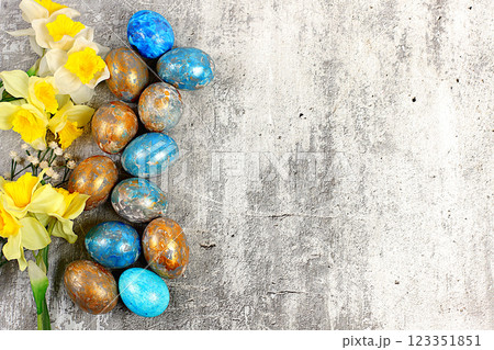 Happy Easter concept. Abstract Easter composition with marbled blue-gray decorated eggs and blooming daffodils, painted with hibiscus flowers. Banner for the screen with space for greeting text, 123351851