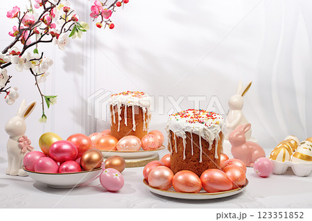 Abstract Easter composition with traditional Russian kulich with meringue and decorated eggs on elegant kitchen table with spring sakura flowers. Happy Easter concept. Screen banner 123351852