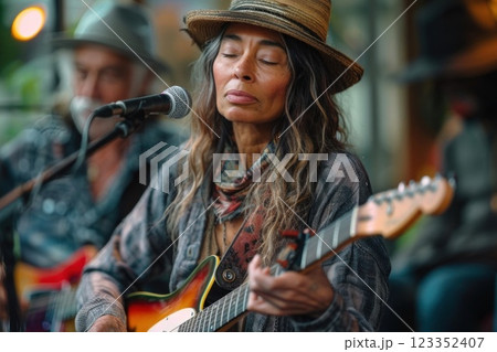 Focused Female Musician Playing Guitar and Singing at Outdoor Venue 123352407