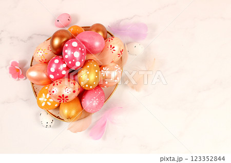 Happy Easter concept.Abstract Easter composition with pink and gold decorated eggs and feathers in a cup. Screen banner with space for greeting text Happy Easter concept.Abstract Easter composition with pink and gold decorated eggs and feathers in a cup. Screen banner with space for greeting text 123352844