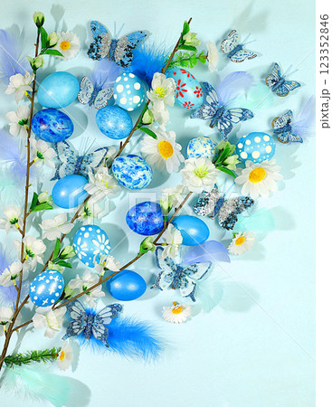Abstract spring easter composition with blue painted eggs, feathers, butterflies, flowering branches and flowers. Happy easter concept. Screen banner 123352846