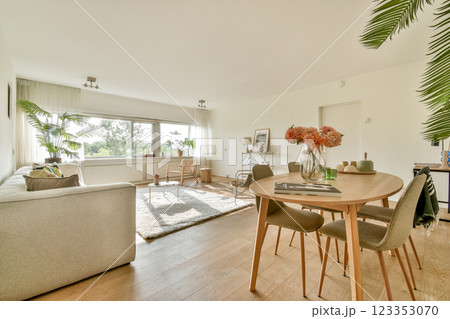 A spacious and stylish living area featuring a light-colored sofa, natural light, and decorative plants, creating a warm, inviting atmosphere. 123353070