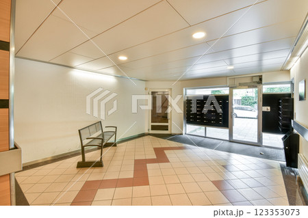 A contemporary indoor lobby featuring sleek design elements, including a patterned floor and a bench, complemented by mailboxes for residents. A contemporary indoor lobby featuring sleek design elements, including a patterned floor and a bench, complemented by mailboxes for residents. 123353073