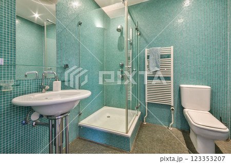 A contemporary bathroom featuring a turquoise tile design, glass shower enclosure, and sleek sanitary ware for a fresh and vibrant look. A contemporary bathroom featuring a turquoise tile design, glass shower enclosure, and sleek sanitary ware for a fresh and vibrant look. 123353207