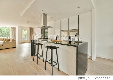 A stylish modern kitchen featuring a central island bar, sleek cabinets, and an open layout, creating a spacious and inviting cooking area. 123353337