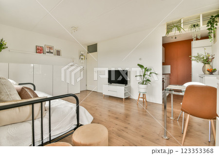 Bright and airy room featuring minimalist decor, wooden flooring, and tasteful furnishings creating a cozy atmosphere for relaxation and living. 123353368