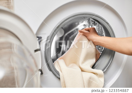 Woman putting white wool clothes into the washing machine, close-up 123354887