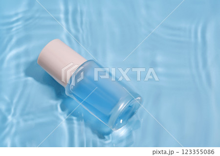Bottle with moisturizing serum in water on blue background. 123355086