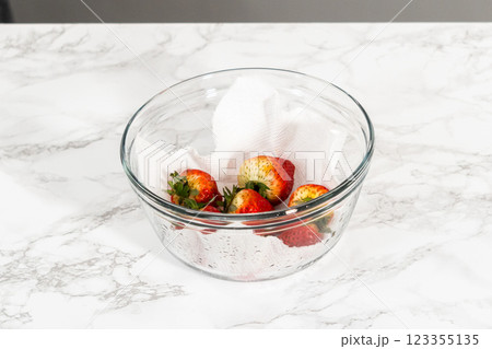 Freshly washed and dried strawberries are carefully arranged in a glass bowl lined with paper towel, ready for snacking or further use. Freshly washed and dried strawberries are carefully arranged in a glass bowl lined with paper towel, ready for snacking or further use. 123355135