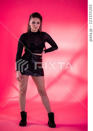 A Youthful Fashion Model Posing Confidently Against a Vibrant Pink Background Setting A Youthful Fashion Model Posing Confidently Against a Vibrant Pink Background Setting 123355203