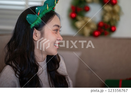 Young Woman in Christmas Tiara Enjoying Festive Holiday Atmosphere at Home Young Woman in Christmas Tiara Enjoying Festive Holiday Atmosphere at Home 123356767