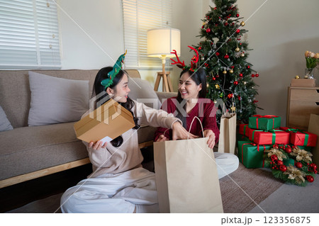 Festive Holiday Celebration with Friends Exchanging Gifts by a Decorated Christmas Tree in Cozy Living Room Festive Holiday Celebration with Friends Exchanging Gifts by a Decorated Christmas Tree in Cozy Living Room 123356875