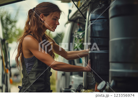 Woman handling a black water tank in a mobile van at an outdoor location 123356974