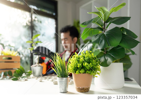 Garden Enthusiast Working Amidst Indoor Plants with Nature Focus Garden Enthusiast Working Amidst Indoor Plants with Nature Focus 123357034