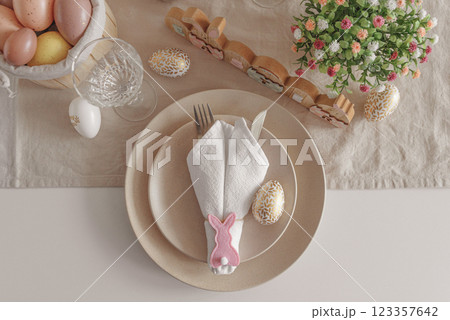 Festive Easter table setting with Easter bunny made from napkin. Easter celebration concept. Top view Festive Easter table setting with Easter bunny made from napkin. Easter celebration concept. Top view 123357642