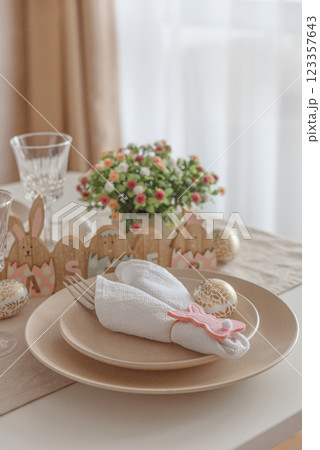 Festive Easter table setting with Easter bunny made from napkin. Easter celebration concept 123357643