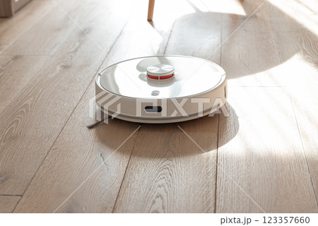 Robot vacuum cleaner vacuuming dust at room. Natural sunny lights 123357660