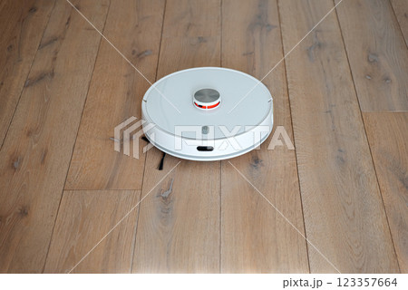 Robot vacuum cleaner vacuuming dust at room. Natural sunny lights Robot vacuum cleaner vacuuming dust at room. Natural sunny lights 123357664