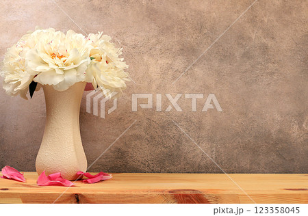 Abstract floral arrangement, empty wooden table and fresh peony flowers in vase, stage for product display and business concept. Minimal modern aesthetics. elegant beauty concept, selective focus 123358045